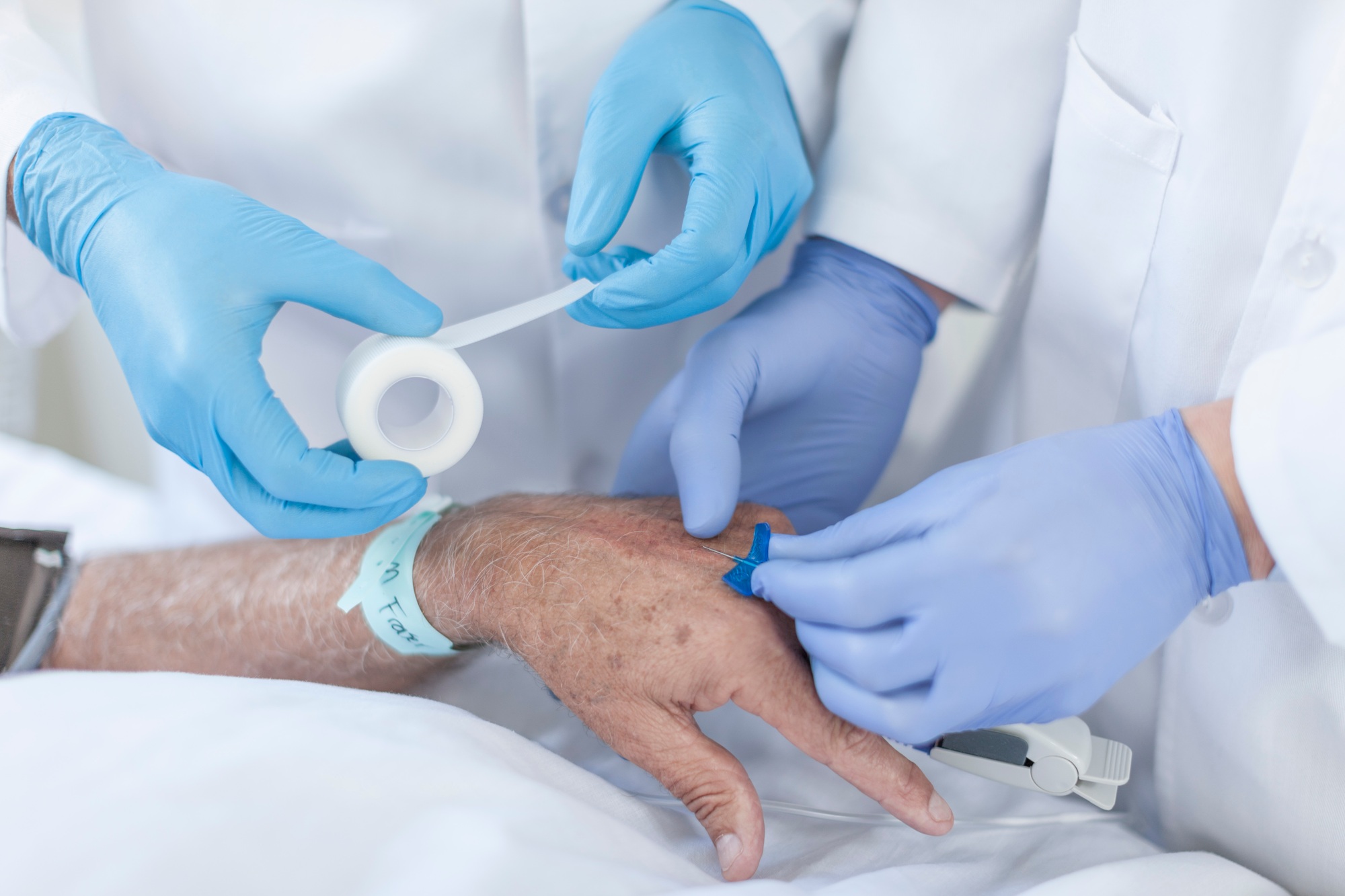 Nurse inserting IV needle in patients hand
